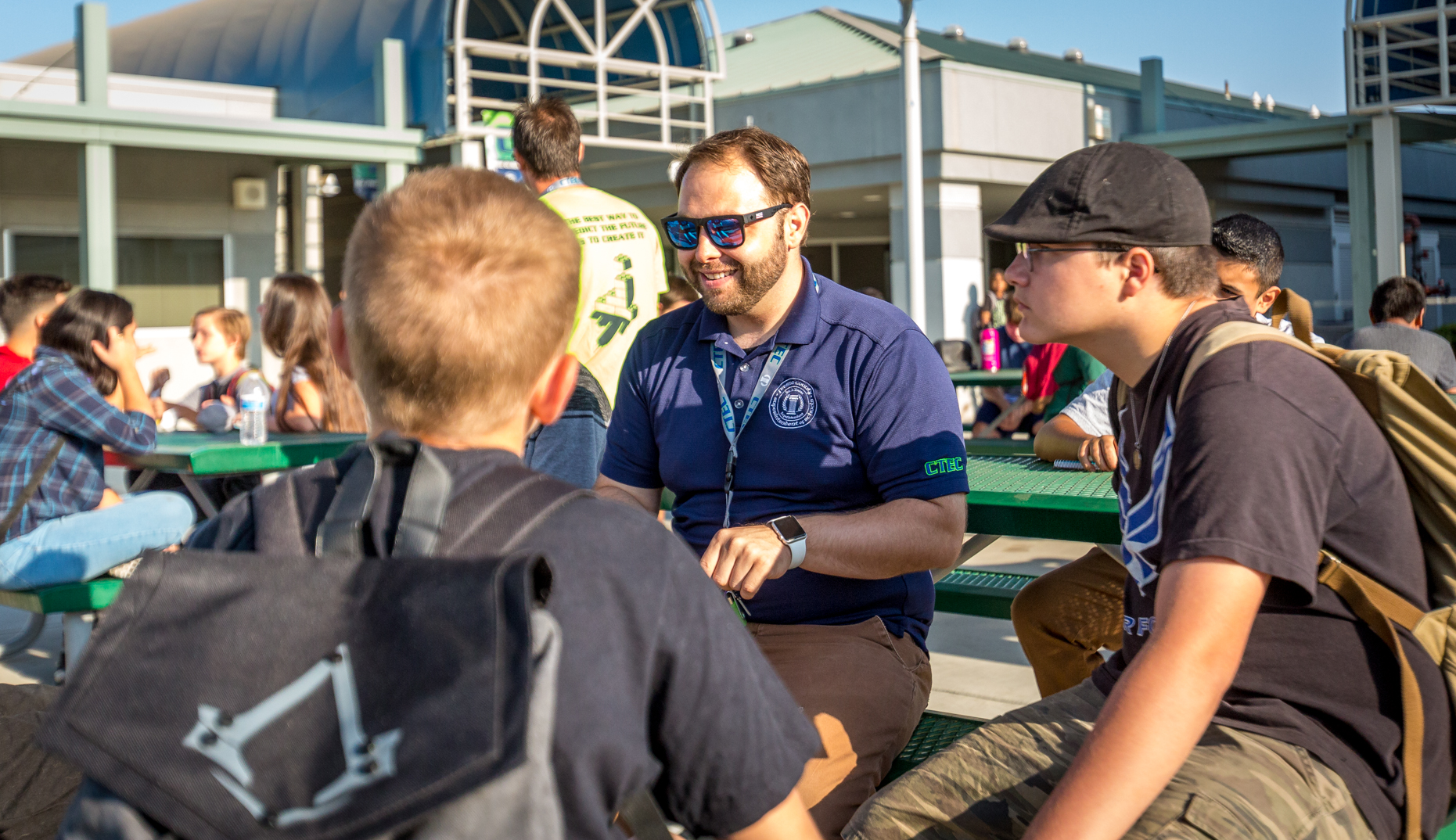 Photo of two students sitting outside with a teacher at CTEC