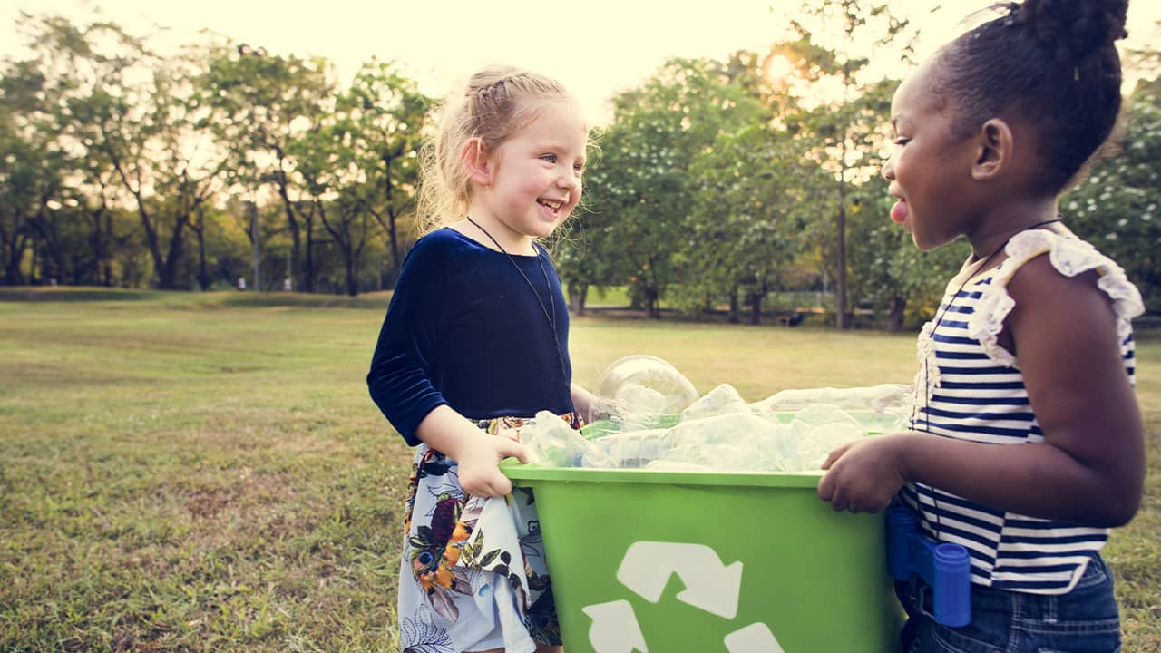 Photo of two young girls holding a recycling bin