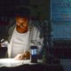 Photo of Carlos Lama using an LED lamp and his phone in his restaurant
